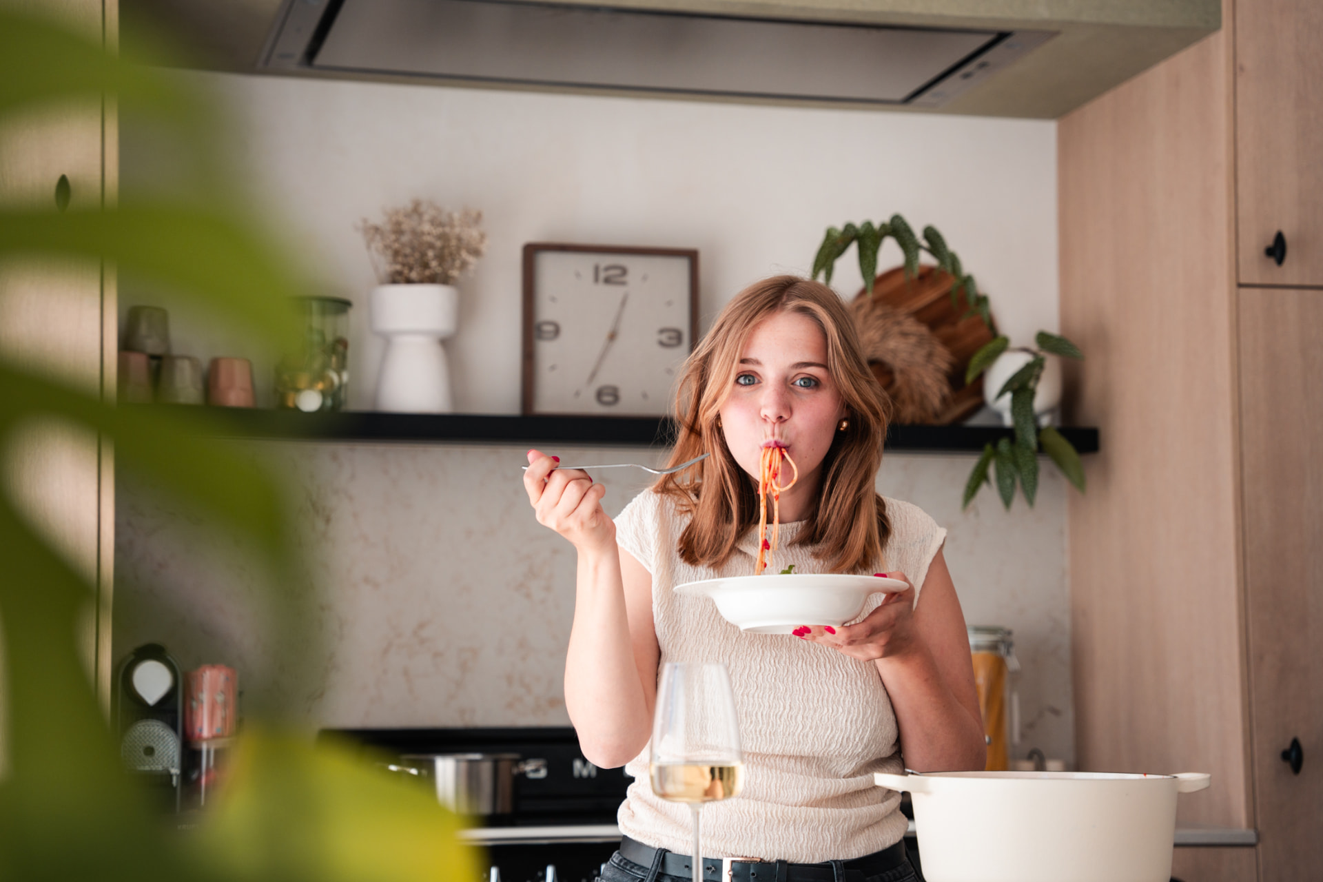 Vrouw die pasta eet in een lichte keuken